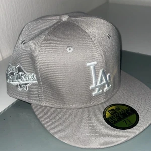 Grå New Era 59FIFTY keps - Säljs  på grund av fel storlek, helt ny keps. Snygg grå New Era 59FIFTY keps med LA-logga framtill. Kepsen har en klassisk passform och är i nytt skick. 