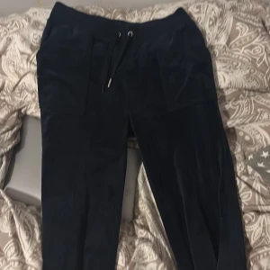 Svarta mjukisbyxor från Juicy Couture - Säljer ett par svarta mjukisbyxor från Juicy Couture i storlek S. De är superbekväma med dragsko i midjan och har en avslappnad passform. Perfekta för mysiga dagar hemma eller en avslappnad dag ute.