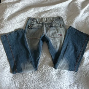 Lågmidjade bootcut jeans  - Säljer ett par snygga blå vintage bootcut jeans. De har en cool tvättad look och är i bra skick. De har några få slitningar längst ner då de släpar lite i marken (långa), men tycker bara det är snyggt slitage. Midjemått: 39 cm. Innerbenslängd: 83 cm. 