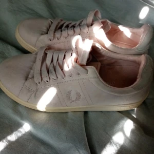 Ljusa sneakers från Fred Perry - Säljer ett par ljusa sneakers från Fred Perry i bra skick. De har en stilren design med snörning och det klassiska Fred Perry-logotypen på sidan. Perfekta för vår och sommar! Skorna är bekväma och passar till de flesta outfits.