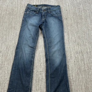 Blå jeans från Lee - Säljer ett par klassiska blå jeans från Lee i bra skick. De har en bootcut passform och är tillverkade i slitstarkt denim. Perfekta för vardagsbruk och kan matchas med det mesta i garderoben. Jeansens design är tidlös med fem fickor och en knappgylf.