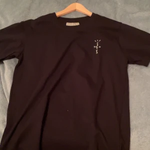 Svart t-shirt med tryck - Säljer en svart t-shirt i bomull med ett coolt tryck på både fram- och baksidan. Perfekt för en avslappnad stil eller att bära till vardags. T-shirten har en normal passform och korta ärmar. Skön och enkel att matcha med jeans eller shorts.