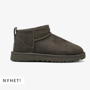 Grå UGG Boots W Classic Ultra Mini - Snygga och bekväma UGG Boots i modellen Classic Ultra Mini. De är i en stilren grå färg och tillverkade i mjuk mocka med en varm och gosig insida. Perfekta för kyliga dagar när du vill hålla fötterna varma och sköna. Nyhet i sortimentet!