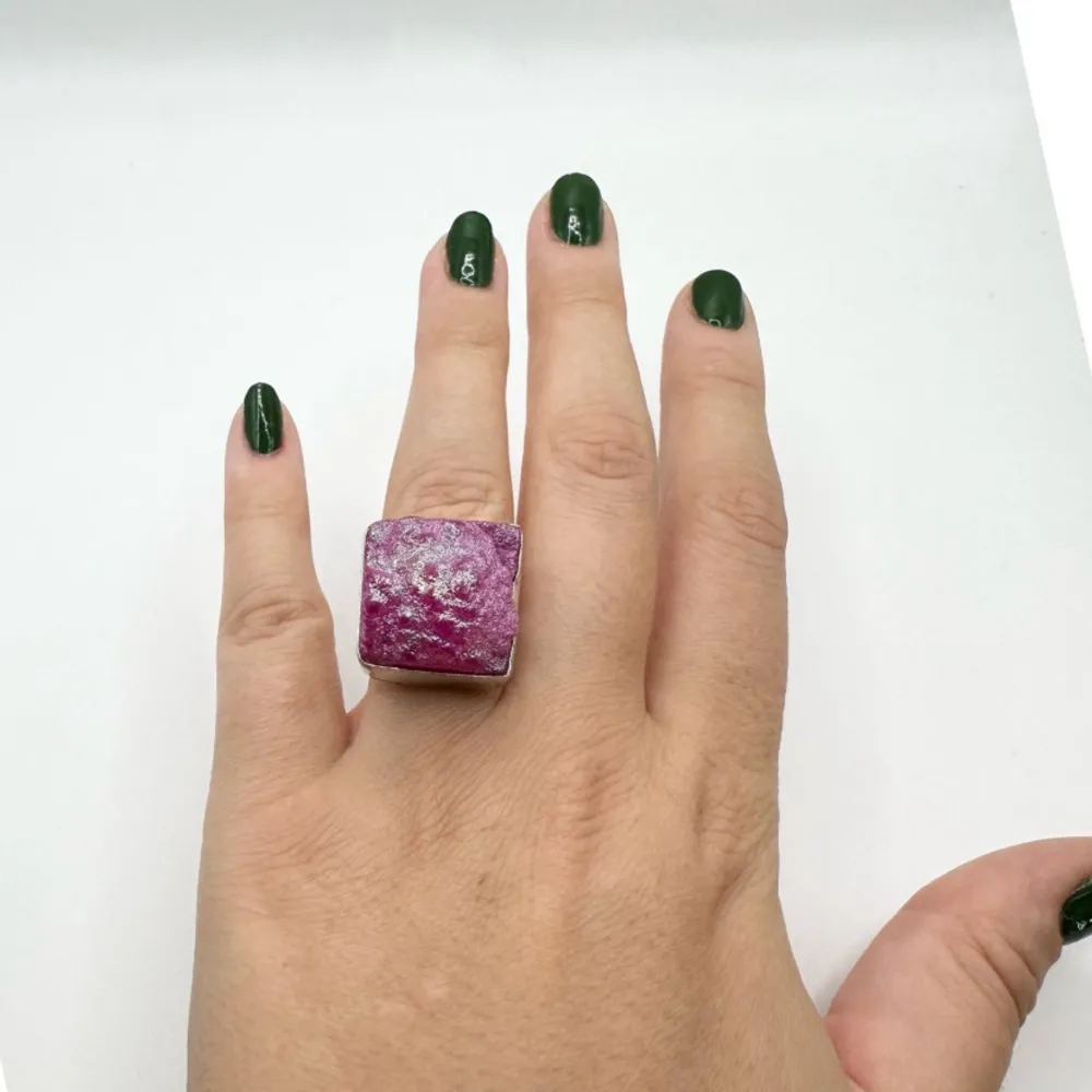 Säljer en supercool ring med en stor, fyrkantig rosa sten. Stenen har en rå och glittrig yta som verkligen fångar ögat. Ringen är i metall och har en robust design som gör den perfekt för att sticka ut på festen eller till vardags. Passar perfekt för dig som älskar statement-smycken!. Accessoarer.