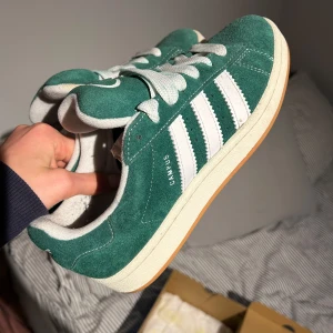Gröna Adidas Campus sneakers - Säljer ett par snygga gröna Adidas Campus sneakers i mocka. De har de klassiska vita ränderna och en vit sula. Skorna är i bra skick, använda fåtal gånger. De kommer med extra gröna skosnören. 