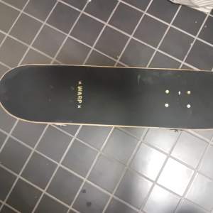 Säljer en cool skateboard från Warp med ett unikt mönster på undersidan.' och är utrustad med vita hjul och stabila truckar. Perfekt för både nybörjare och erfarna åkare som vill ha stil och funktion i ett. Bra skick, knappt använd