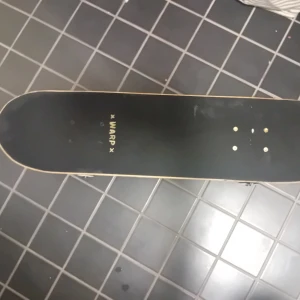 Skateboard från Warp med unikt mönster - Säljer en cool skateboard från Warp med ett unikt mönster på undersidan.' och är utrustad med vita hjul och stabila truckar. Perfekt för både nybörjare och erfarna åkare som vill ha stil och funktion i ett. Bra skick, knappt använd