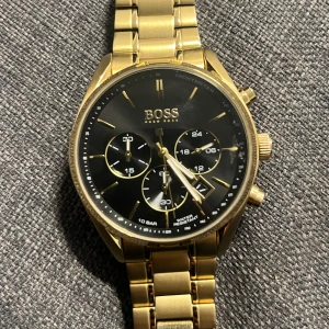 Guldfärgad klocka från Hugo boss - Säljer en stilren guldfärgad klocka från HUGO BOSS Som inte tillverkas längre med svart urtavla och tre mindre urtavlor för extra funktioner. Klockan helt ny kostar 6300kr 