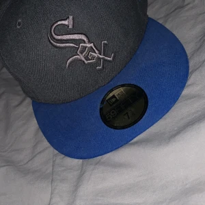 Grå och blå keps från New Era - Säljer en snygg grå keps med blå skärm från New Era. Den har en broderad logga på framsidan och MLB-logga baktill. Pris kan diskuteras.