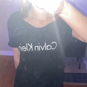 Svart t-shirt från Calvin Klein - Säljer en svart t-shirt från Calvin Klein i mycket bra skick. Den har en klassisk design med korta ärmar och märkesloggan tryckt i vitt på framsidan. Perfekt för en casual look eller att matcha med jeans för en avslappnad stil.