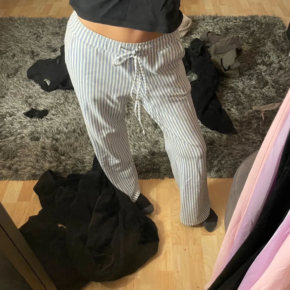 Säljer ett par superbekväma randiga byxor i vitt och blått. Pyjamasbyxor som är supermjuka från design by si. Byxorna har en snörning i midjan för justerbar passform.. Farkut & Housut.