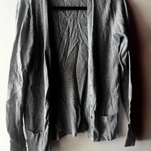 Grå kofta från Zara - Säljer en stilren grå kofta från Zara i mycket bra skick. Den har långa ärmar och praktiska fickor framtill. Perfekt för både höst och vår, och den är gjord i ett mjukt bomullsmaterial. Passar till både vardag och lite finare tillfällen. 🩶