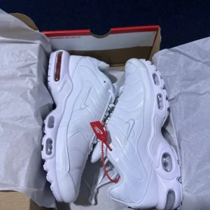 Vita Nike sneakers - Säljer ett par helt nya vita Nike sneakers i originalkartong. Skorna har en snygg och modern design med synliga luftkuddar i sulan för extra komfort. Perfekta för både vardag och träning. De har snörning och en diskret Nike-logga på sidan.