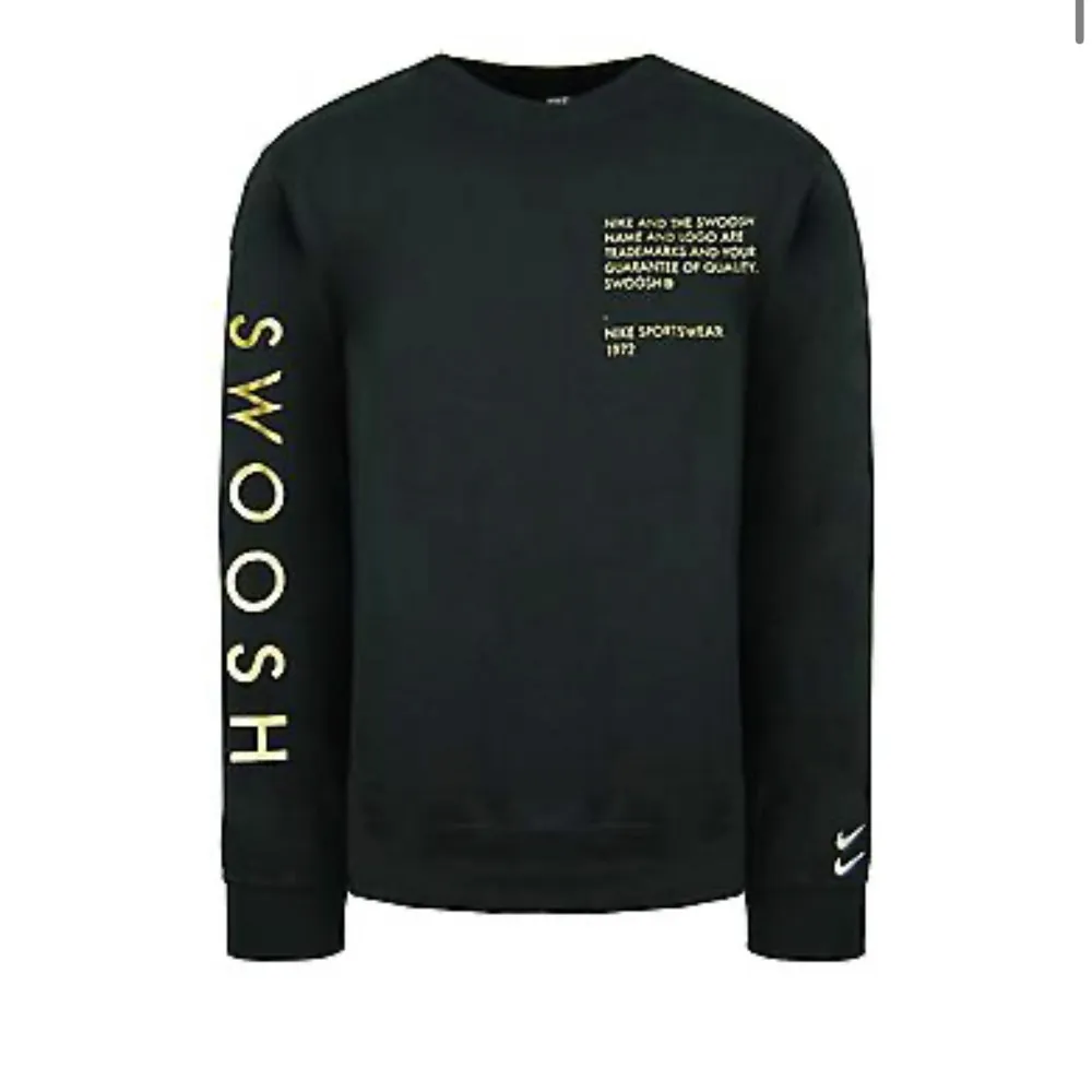 Säljer en svart sweatshirt från Nike med texten 'SWOOSH' i gult på ärmen och ett tryck på bröstet. Tröjan är i bra skick och perfekt för höst och vinter. Den har långa ärmar och en klassisk rund halsringning. Perfekt för en casual look eller träning!. Tröjor & Koftor.