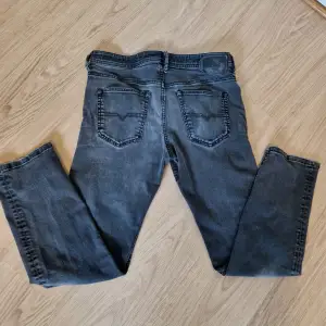 Säljer ett par grå jeans från Diesel i bra skick. Storlek w33 l32. De har en cool sliten look med en liten reva på ena benet. Perfekta för en avslappnad stil! Passar bra till både vardag och fest.