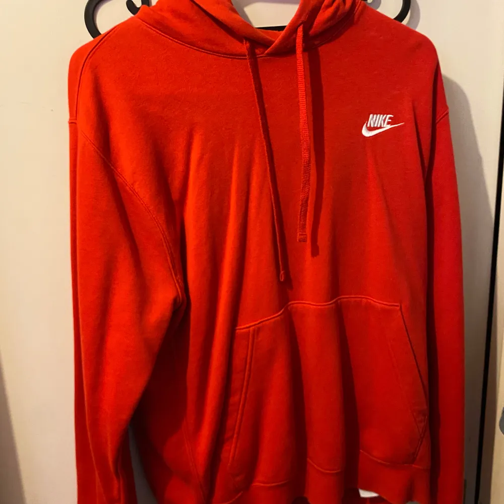 Säljer en snygg röd hoodie från Nike i mycket bra skick. Den har en klassisk design med en stor ficka fram och justerbar huva. Perfekt för både vardag och träning. Nike-loggan är broderad i vitt på bröstet. Passar perfekt för höst och vinter!. Tröjor & Koftor.