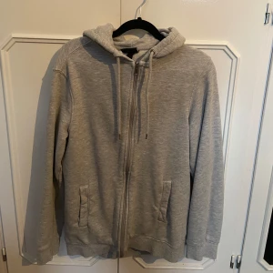 Grå hoodie från H&M - En grå zip hoodie från hm, helt oanvänd då den är 1 storlek för stor för mig. Den har enbart hängt i min garderob!