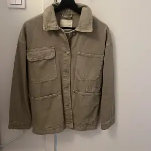 Säljer en snygg beige jacka från Pull&Bear i storlek S. Jackan har en avslappnad stil med stora fickor och knappar framtill. Perfekt för höst och vår, och den är i mycket bra skick. Passar både till vardags och lite mer uppklädda tillfällen.