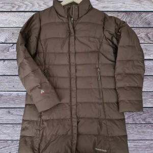 Brun dunjacka från Mont-bell - Säljer en brun dunjacka från Mont-bell i storlek L. Jackan har en stilren design med dragkedja och långa ärmar. Perfekt för kalla vinterdagar med sin varma och bekväma passform. Den är i mycket bra skick och redo för nya äventyr!