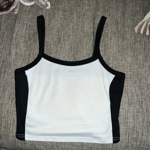 Basic linne -  Den har en enkel och stilren design med svart kant runt halsen och ärmarna.