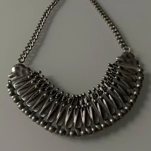 Unikt silverfärgat halsband - Säljer ett coolt och unikt halsband i silverfärg. Det har en chunky kedja och en detaljrik design med droppformade hängen och små kulor. Perfekt för att ge din outfit en edgy touch. Passar både till vardags och fest!