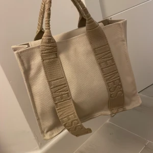 Zara väska  - Säljer en snygg beige väska i  bra skick. Väskan har en justerbar axelrem för extra bekvämlighet och en liten tygbit att knäppa ihop handtagen med!✨😍