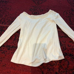 Vit långärmad topp - Säljer en stilren vit långärmad topp i mjukt material. Perfekt för både vardag och festliga tillfällen. Toppen har en enkel design med en bekväm passform. Passar bra till jeans eller kjol för en avslappnad look.