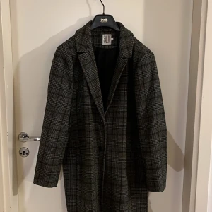 Rutig kappa från Saint Tropez - Säljer en snygg rutig kappa från Saint Tropez i storlek L. Perfekt för höst och vår med sitt klassiska mönster och långa ärmar. Kappan har en stilren design med knappar framtill. Passar både till vardags och festliga tillfällen. 🖤