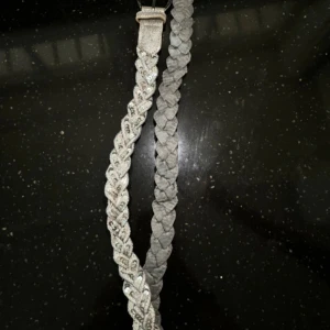 Flätat glittrigt bälte - Säljer ett snyggt flätat bälte i silver med glittriga detaljer. Perfekt för att piffa upp vilken outfit som helst! Bältet har ett runt spänne och är i mycket bra skick. 