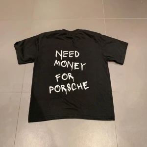 Need Money For Porsche” T-Shirt  - Säljer en svart t-shirt med texten 'Need Money for Porsche' i vit på baksidan. Den har en normal passform och är kortärmad, perfekt för en avslappnad stil. T-shirten är i bra skick och gjord av bomull, vilket gör den bekväm att bära.