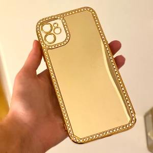 Guldig mobilskal med strassdetaljer - Snyggt och glittrigt mobilskal i guld med strassdetaljer runt kanterna och kameran. Perfekt för att ge din telefon en lyxig look. Skalet är både stilrent och skyddande, och passar perfekt för festliga tillfällen. Gör din mobil till en riktig showstopper!