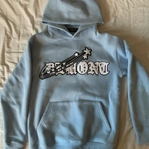 Ljusblå hoodie från Demont - Säljer en snygg ljusblå hoodie från Demont i storlek XS. Perfekt för en avslappnad stil och passar bra till både höst och vår. Huvan är mjuk och bekväm, perfekt för kyliga dagar.