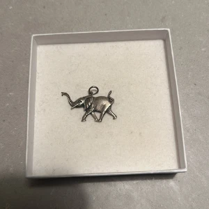 Silverfärgad elefantberlock - Söt liten elefantberlock i silverfärg, perfekt för att sätta på ett armband eller halsband. Den har fina detaljer och är i mycket bra skick. En fin present eller ett charmigt tillskott till din smyckessamling!