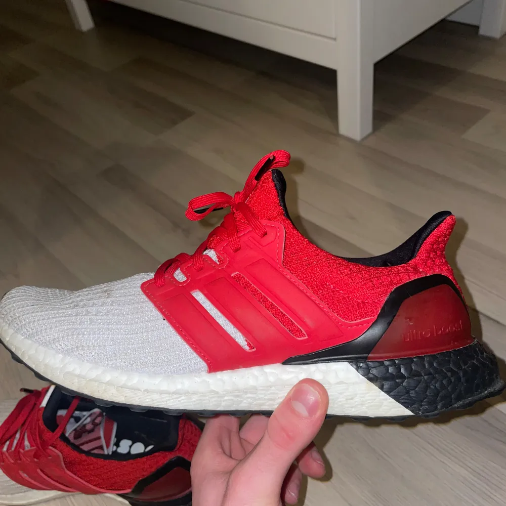 Säljer ett par Adidas Ultraboost i snyggt rött och vitt. Skorna har en bekväm och responsiv sula, perfekt för löpning eller vardagsbruk. De är i bra skick med lite små smutsfläckar. (Går säkert göra rent lite). Inga slitningar på tyg eller sula. Otroligt sköna skor som du inte tröttnar på att gå i. . Skor.