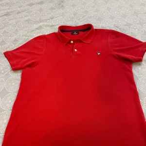 Röd pikétröja från U.S. Polo Assn. - Säljer en snygg röd pikétröja från U.S. Polo Assn. med klassisk krage och knappar. Tröjan har en broderad logga på bröstet och är i mycket bra skick. Perfekt för både vardag och fest! 🔥