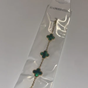 Armband i rostfritt stål med gröna klöver - Snyggt armband i rostfritt stål med flera gröna klöverformade hängen. Perfekt för att ge en färgklick till din outfit. Armbandet har en elegant kedja och är lätt att matcha med andra smycken. Passar både till vardags och fest!