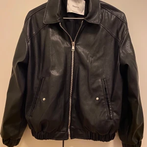 Svart skinnjacka från Bershka - Säljer en snygg svart skinnjacka från Bershka i storlek XS.  Perfekt för höst och vår, med en klassisk look som funkar till allt. 
