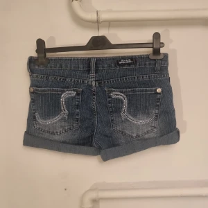Blå jeansshorts med pärldetaljer - Säljer ett par blå jeansshorts från Hollister i mycket bra skick. De har pärldetaljer på bakfickorna och en klassisk femficksdesign.