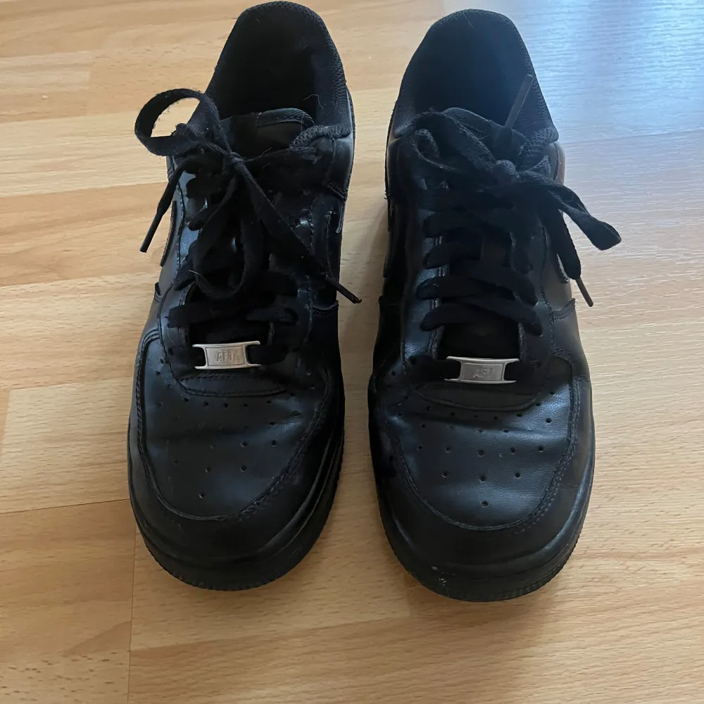 Säljer ett par svarta Nike Air Force sneakers i bra skick. De har en klassisk design med snörning och är perfekta för vardagsbruk. Skorna har en bekväm passform. Perfekta för både höst och vår!. Skor.