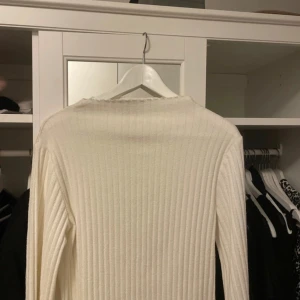 Vit ribbad tröja och tillhörande kjol  - Säljer en stilren vit ribbad tröja i mycket bra skick. Den är långärmad och perfekt för både höst och vinter. Tröjan är gjord i ett mjukt material som känns skönt mot huden. Passar bra till både vardag och fest! Det tillkommer en kjol i samma material, ett sett 