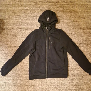 Svart hoodie från Sail Racing - Säljer en svart hoodie från Sail Racing med dragkedja och huva. Bra skick. Storlek 170.