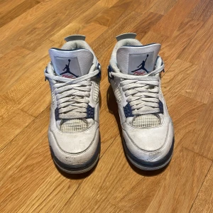 Nike Air Jordans i vit och blå - Snygga Nike Air Jordans i vit med blå detaljer. Skorna har klassisk snörning och en stilren design med det ikoniska Jumpman-loggan. Perfekta för sneaker-entusiaster!