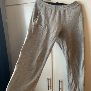 Grå mjukisbyxor från Kappa - Säljer ett par grå mjukisbyxor från Kappa med låg midja och det klassiska Kappa-logotypen på.