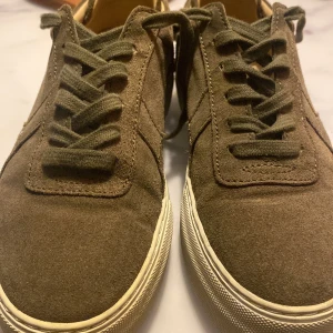 Bruna sneakers från Axel Arigato - Snygga bruna sneakers i mocka från Axel Arigato med snörning. Perfekta för en stilren look.