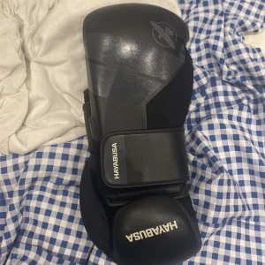 Svarta boxningshandskar från Hayabusa - Säljer ett par svarta boxningshandskar från Hayabusa. De har en stilren design med logotypen tryckt på ovansidan och kardborreband för enkel justering. Perfekta för träning och sparring. Handskarna är 12 Oz och är helt oanvända.