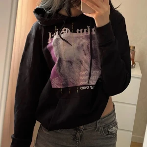 Svart hoodie med tryck - Svart hoodie med tryck i lila och vitt från PrettyLittleThing. Den har en justerbar huva med snören och en stor ficka framtill. Oversized look i strl XS, använd några gånger och i jättebra skick.