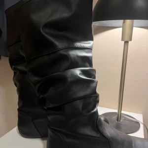 Svarta boots i syntetmaterial - Snygga svarta stövlar i syntetmaterial. Perfekta för att ge en stilren look till din outfit. Dem är använda fåtal gånger och i väldigt fint skick! 🌸Jag säljer då jag tycker dem är lite för korta för min smak😋