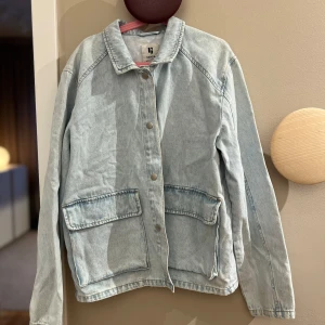 Ljusblå jeansjacka från Garcia - Säljer en stilren ljusblå jeansjacka från Garcia. Jackan har en klassisk krage och knappar framtill. Två stora fickor framtill ger en cool look. Perfekt för vår och sommar! Storlek 176 passar mig som har xs/s köptes i somras bara använd 1 gång 