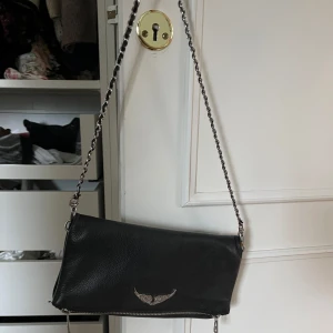 Svart Zadig väska - Snygg svart Zadig i skinn med en cool kedjerem. Väskan är i i mycket bra skick förutom på märket har lite av färgen försvunnit runtom de sista bilden
