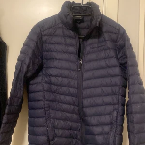 Mörkblå dunjacka från Peak Performance - Säljer en mörkblå dunjacka från Peak Performance. Jackan har en dragkedja framtill och är quiltad för extra värme. Perfekt för kyligare dagar med sin långa ärm och stilrena design. Jackan är i storlek 170 som motsvarar ungefär M/L . Ett litet hål på vänster arm som knappt syns i verkligheten💓💓
